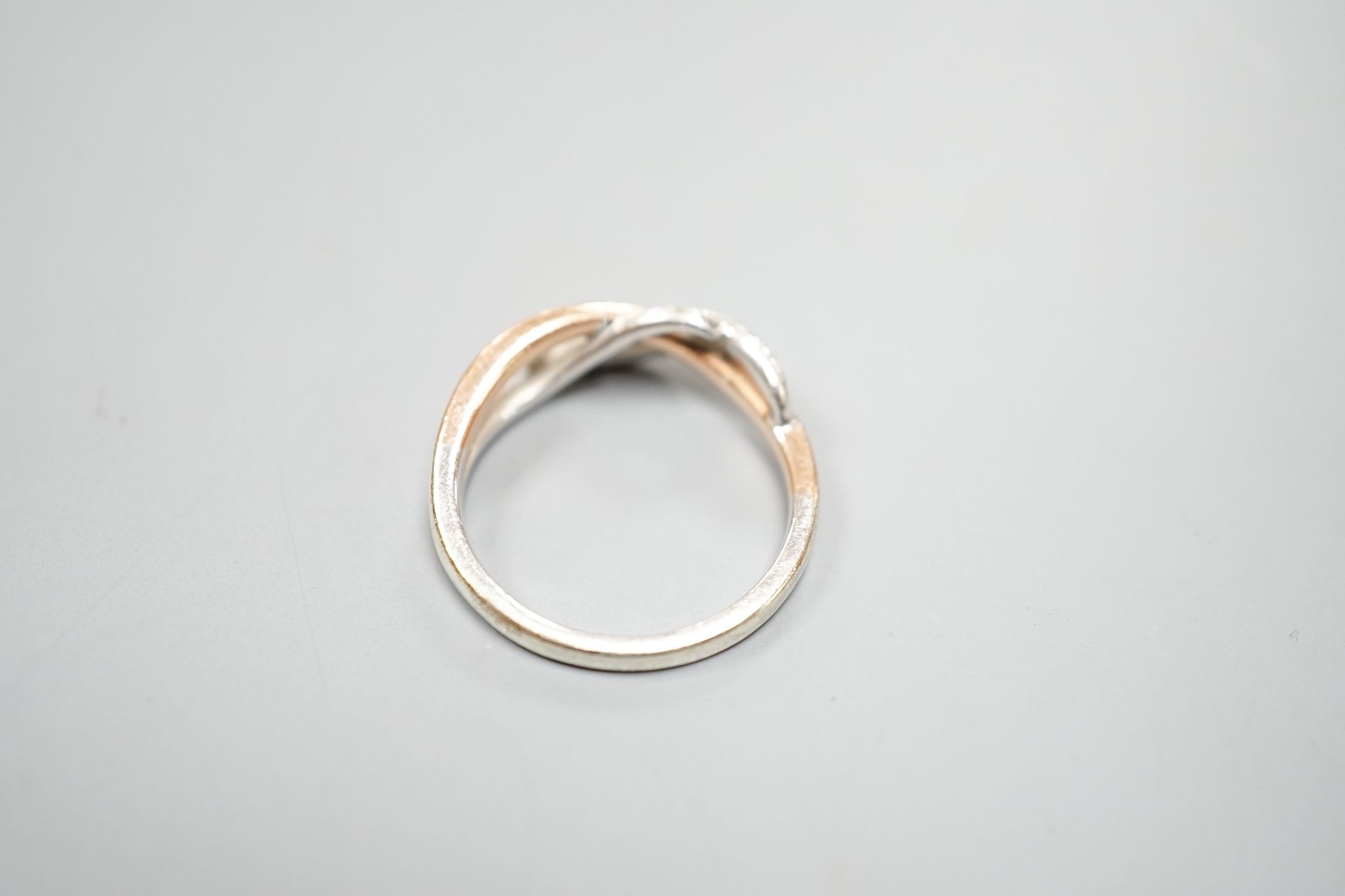 A modern two colour 9ct gold and diamond chip set crossover ring, size Q, gross weight 3.8 grams.